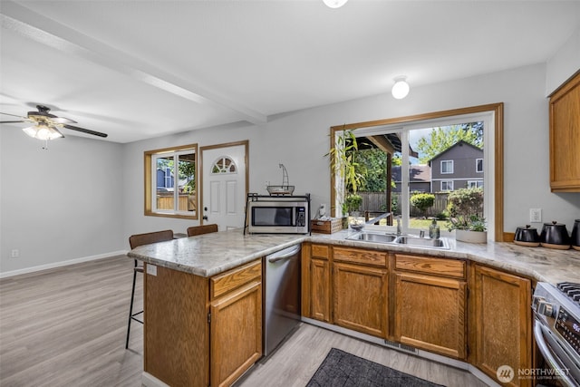 6218 199th Street Ct E, Spanaway, WA 98387 - kitchen featuring stainless steel appliances, a peninsula, a kitchen bar, light wood-type flooring, and plenty of natural light