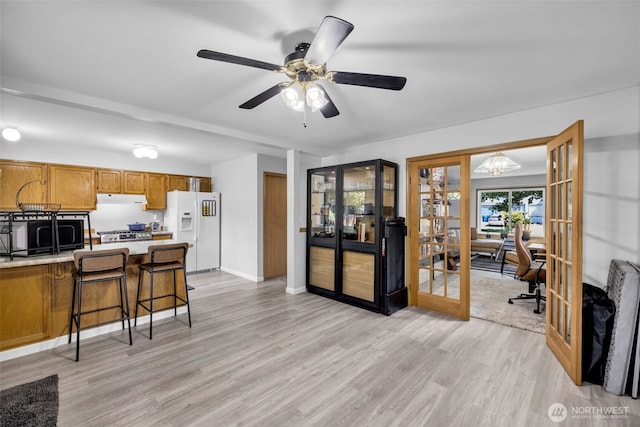6218 199th Street Ct E, Spanaway, WA 98387 - kitchen featuring white refrigerator with ice dispenser, black microwave, under cabinet range hood, light countertops, and light wood-type flooring