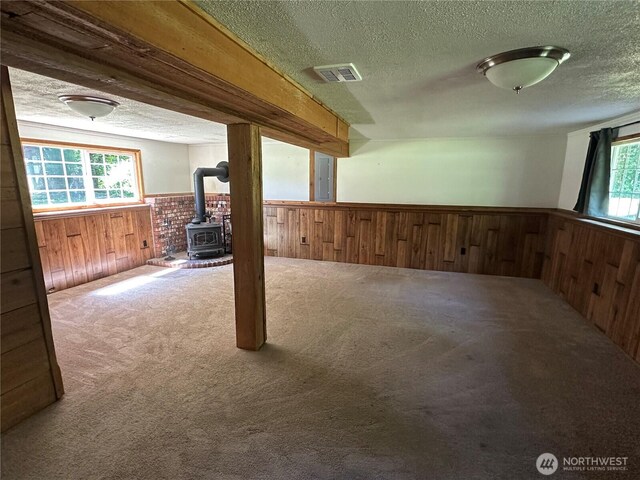 4776 Prairie Ln, Sedro Woolley, WA 98284 - below grade area with wainscoting, wood walls, a wood stove, a textured ceiling, and carpet floors
