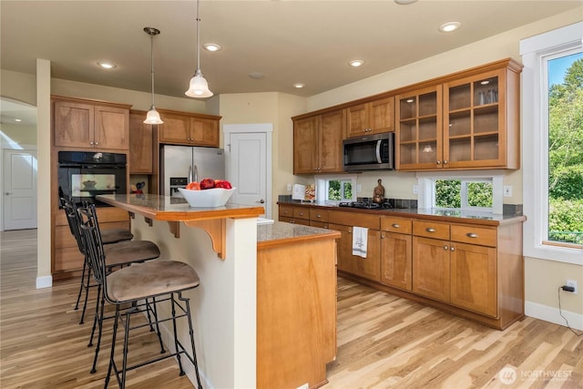 6412 122nd Street Ct E, Puyallup, WA 98373 - kitchen featuring black appliances, brown cabinetry, light wood-style floors, a kitchen bar, and recessed lighting