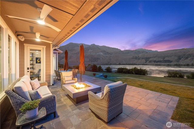 167 N Shore Dr, Orondo, WA 98843 - patio terrace at dusk featuring a patio, a mountain view, a lawn, and an outdoor living space with a fire pit