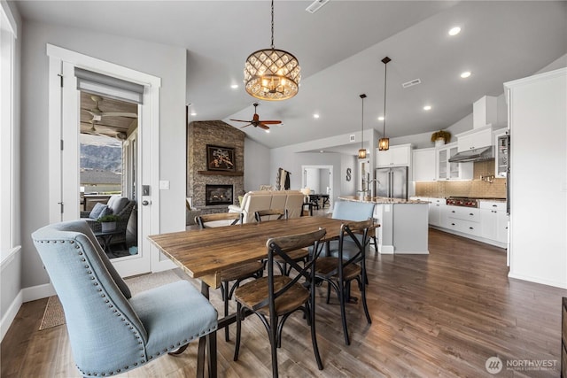 167 N Shore Dr, Orondo, WA 98843 - dining area with ceiling fan, a chandelier, a fireplace, vaulted ceiling, and dark wood finished floors
