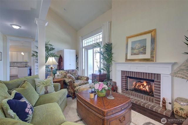 30 Chauncey Ln W, Pacific Beach, WA 98571 - living area with high vaulted ceiling, a brick fireplace, wood finished floors, and ornate columns