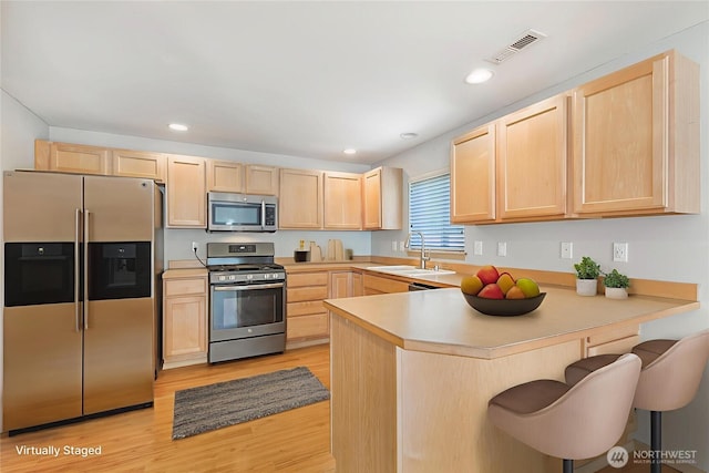 3929 152nd Pl SE, Bothell, WA 98012 - kitchen with stainless steel appliances, light brown cabinetry, a peninsula, light wood finished floors, and light countertops