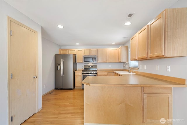 3929 152nd Pl SE, Bothell, WA 98012 - kitchen with light brown cabinets, appliances with stainless steel finishes, light wood-type flooring, light countertops, and a peninsula