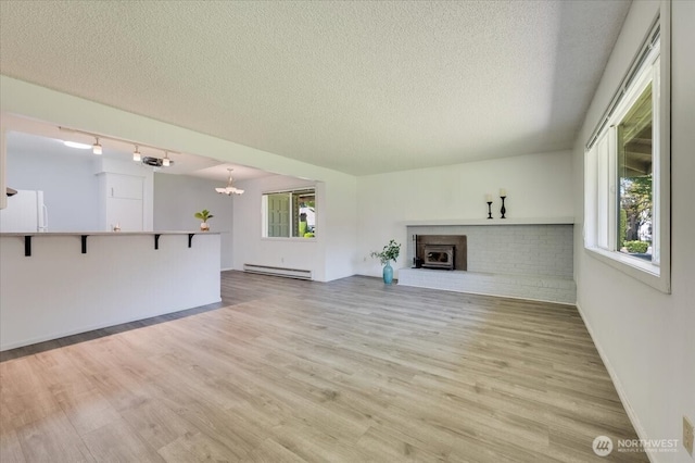 4502 216th St SW Unit 2A, Mountlake Terrace, WA 98043 - unfurnished living room featuring baseboard heating, a textured ceiling, a chandelier, light wood-type flooring, and a fireplace