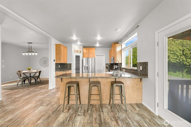 3664 N Red River Rd, Ferndale, WA 98248 - kitchen with appliances with stainless steel finishes, light wood-type flooring, tasteful backsplash, a peninsula, and a kitchen bar