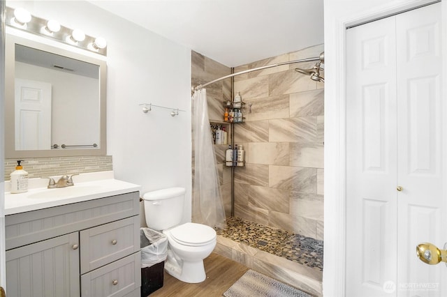 2352 W Covey Dr, Othello, WA 99344 - bathroom featuring vanity, decorative backsplash, a tile shower, toilet, and wood finished floors