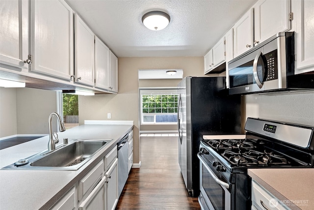 3903 Westpark Ct NW, Olympia, WA 98502 - kitchen with appliances with stainless steel finishes, dark wood-style floors, white cabinetry, light countertops, and a textured ceiling