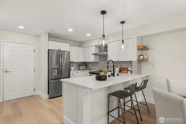 2401 SW Brandon St Unit 210, Seattle, WA 98106 - kitchen with stainless steel fridge with ice dispenser, wall chimney exhaust hood, a peninsula, a kitchen breakfast bar, and white cabinetry