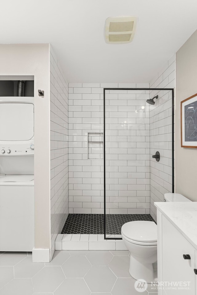 2401 SW Brandon St Unit 210, Seattle, WA 98106 - bathroom featuring stacked washer / drying machine, tiled shower, vanity, and tile patterned floors