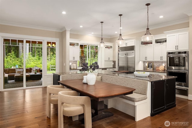 26507 SE Old Black Nugget Rd, Issaquah, WA 98029 - kitchen featuring appliances with stainless steel finishes, a kitchen island, backsplash, glass insert cabinets, and crown molding