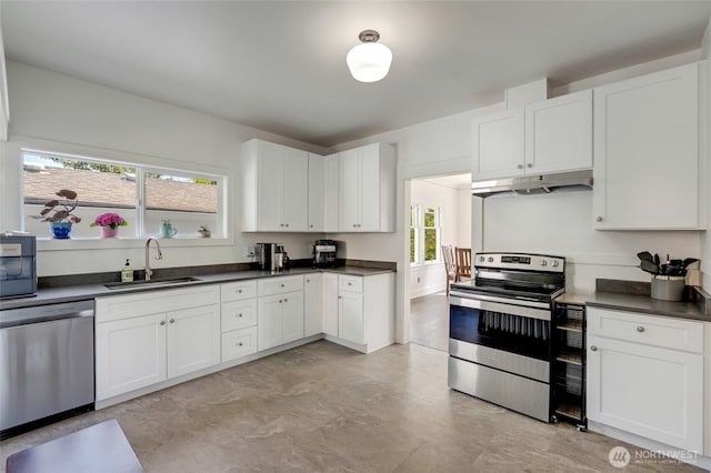 4918 S 3rd Ave, Everett, WA 98203 - kitchen with appliances with stainless steel finishes, under cabinet range hood, dark countertops, and white cabinetry