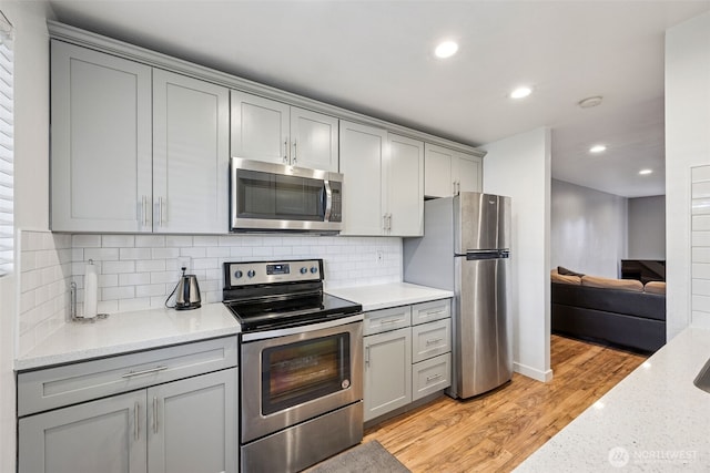 12416 SE 272nd Pl Unit C, Kent, WA 98030 - kitchen featuring stainless steel appliances, gray cabinets, light wood finished floors, recessed lighting, and decorative backsplash