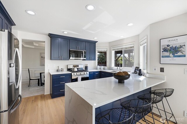 7109 SE 135th Pl, Newcastle, WA 98059 - kitchen with appliances with stainless steel finishes, blue cabinetry, a peninsula, a breakfast bar, and recessed lighting