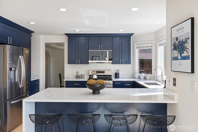 7109 SE 135th Pl, Newcastle, WA 98059 - kitchen with appliances with stainless steel finishes, blue cabinets, a peninsula, a kitchen breakfast bar, and recessed lighting