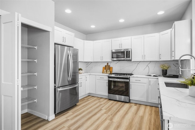 3410 102nd Ave NE, Lake Stevens, WA 98258 - kitchen with appliances with stainless steel finishes, a sink, light wood-style flooring, light stone counters, and backsplash