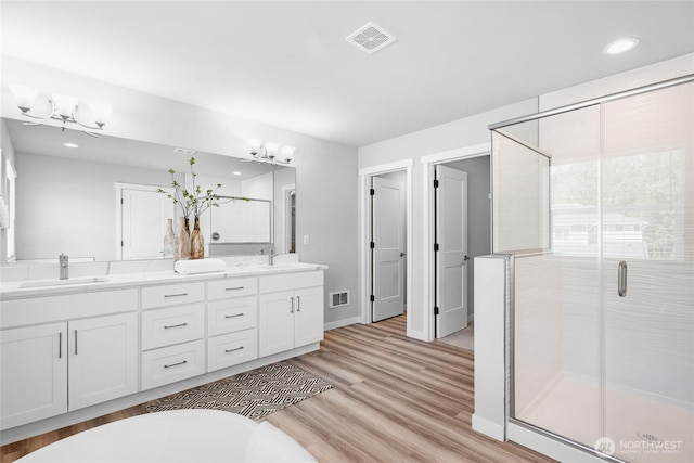 3410 102nd Ave NE, Lake Stevens, WA 98258 - full bath with a chandelier, double vanity, a shower stall, wood finished floors, and recessed lighting
