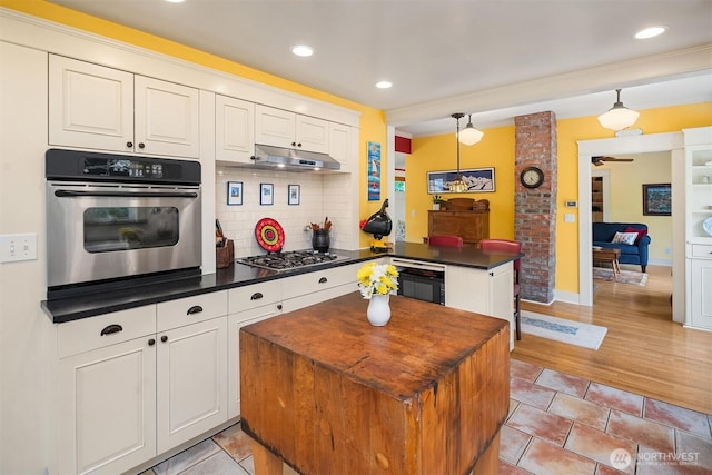 9026 SW 184th St, Vashon, WA 98070 - kitchen featuring stainless steel appliances, dark countertops, under cabinet range hood, decorative backsplash, and white cabinetry