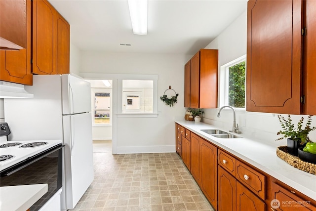 208 Barksdale Ave, Dupont, WA 98327 - kitchen featuring white electric stove, light countertops, under cabinet range hood, and brown cabinets