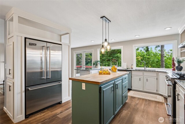 7650 SE Southworth Dr, Port Orchard, WA 98366 - kitchen with stainless steel appliances, wooden counters, dark wood-style floors, a center island, and white cabinetry