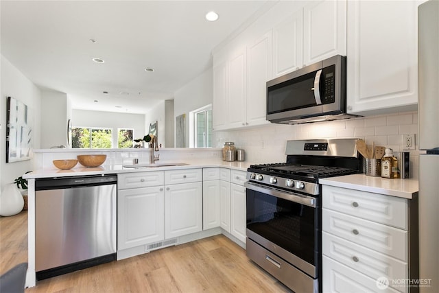 6816 NE 153rd Pl Unit D, Kenmore, WA 98028 - kitchen featuring stainless steel appliances, a sink, a peninsula, light wood-type flooring, and light countertops