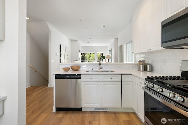 6816 NE 153rd Pl Unit D, Kenmore, WA 98028 - kitchen featuring appliances with stainless steel finishes, a sink, a peninsula, backsplash, and recessed lighting
