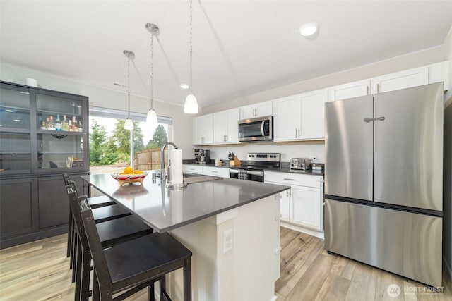15177 Prescott Loop SE, Yelm, WA 98597 - kitchen with stainless steel appliances, white cabinetry, a center island with sink, decorative light fixtures, and light wood-type flooring
