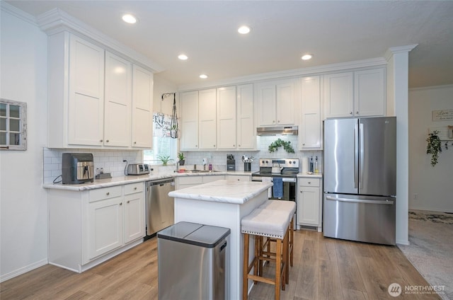 170 E Soundview Dr E, Shelton, WA 98584 - kitchen with appliances with stainless steel finishes, under cabinet range hood, crown molding, light wood finished floors, and decorative backsplash