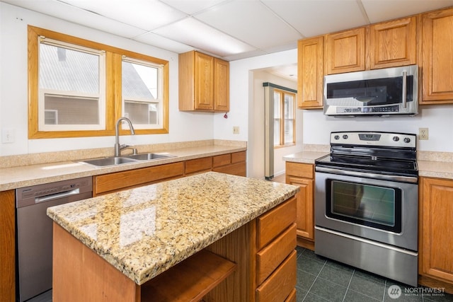 819 1st St, Cle Elum, WA 98922 - kitchen with stainless steel appliances, a paneled ceiling, a kitchen island, dark tile patterned floors, and light stone countertops
