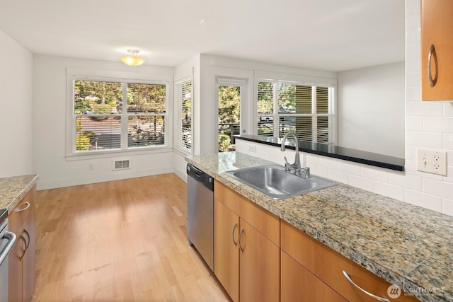 22910 90th Ave W Unit B306, Edmonds, WA 98026 - kitchen with stainless steel dishwasher, decorative backsplash, light wood-style flooring, light stone countertops, and brown cabinetry