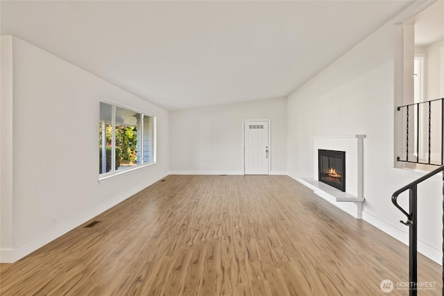 1003 9th St NW, Puyallup, WA 98371 - unfurnished living room with light wood finished floors, a glass covered fireplace, and lofted ceiling