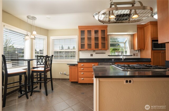 1016 N Madison St, Tacoma, WA 98406 - kitchen featuring appliances with stainless steel finishes, brown cabinets, dark countertops, glass insert cabinets, and decorative backsplash