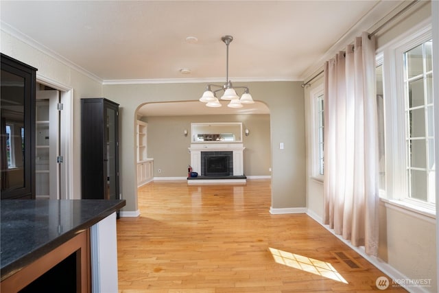 1016 N Madison St, Tacoma, WA 98406 - unfurnished living room featuring arched walkways, ornamental molding, light wood-type flooring, a chandelier, and a fireplace with raised hearth