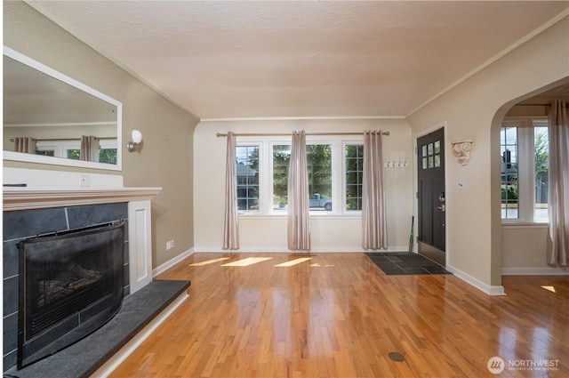 1016 N Madison St, Tacoma, WA 98406 - unfurnished living room featuring arched walkways, a fireplace with raised hearth, wood finished floors, plenty of natural light, and ornamental molding