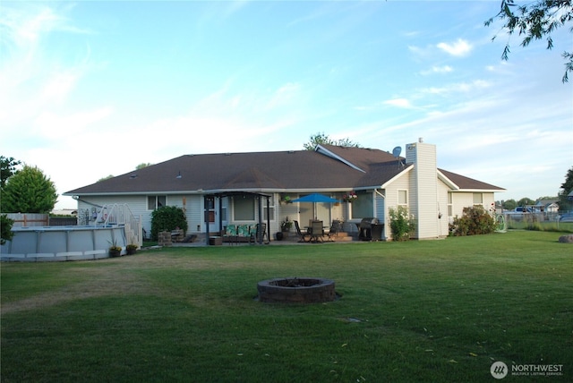 3081 Wild Goose Rd NE, Moses Lake, WA 98837 - rear view of property featuring an outdoor fire pit, a lawn, an outdoor pool, a patio, and a chimney