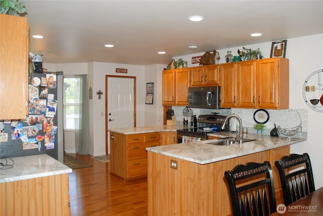 3081 Wild Goose Rd NE, Moses Lake, WA 98837 - kitchen featuring black appliances, a peninsula, light wood-style flooring, tasteful backsplash, and light stone countertops
