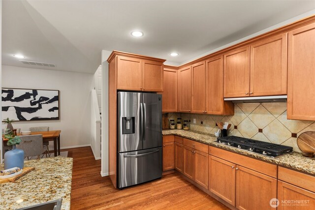 11734 167th Ct NE, Redmond, WA 98052 - kitchen with appliances with stainless steel finishes, tasteful backsplash, ventilation hood, light stone counters, and light wood-style flooring