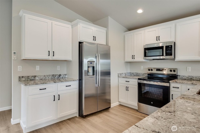 356 N Wynoochee Dr SW, Ocean Shores, WA 98569 - kitchen with appliances with stainless steel finishes, light wood finished floors, white cabinetry, light stone counters, and recessed lighting