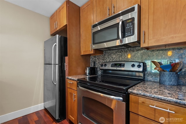 8503 Bowdoin Way Unit 203, Edmonds, WA 98026 - kitchen with appliances with stainless steel finishes, dark wood-type flooring, tasteful backsplash, baseboards, and dark stone countertops