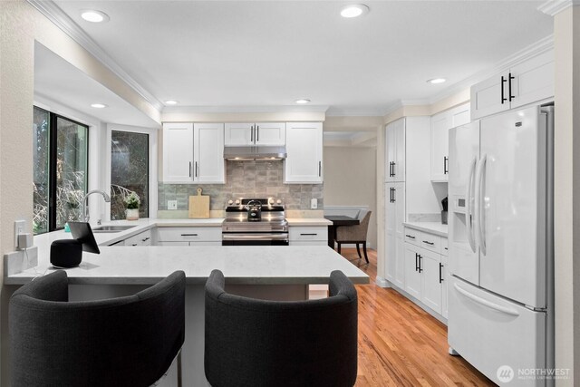 5610 S 296th Ct, Auburn, WA 98001 - kitchen featuring white refrigerator with ice dispenser, stainless steel electric range oven, crown molding, light wood-style floors, and white cabinetry