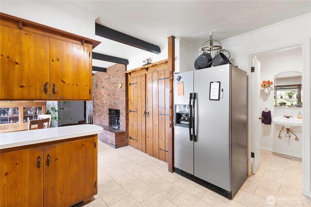 8415 57th Ave E, Puyallup, WA 98371 - kitchen with stainless steel fridge with ice dispenser, light tile patterned flooring, a brick fireplace, brown cabinets, and beamed ceiling