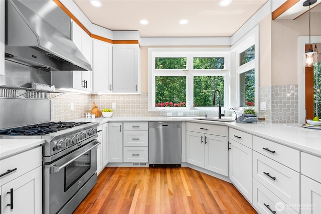 13730 Main St, Bellevue, WA 98005 - kitchen featuring stainless steel appliances, wall chimney range hood, white cabinets, light wood-style flooring, and recessed lighting