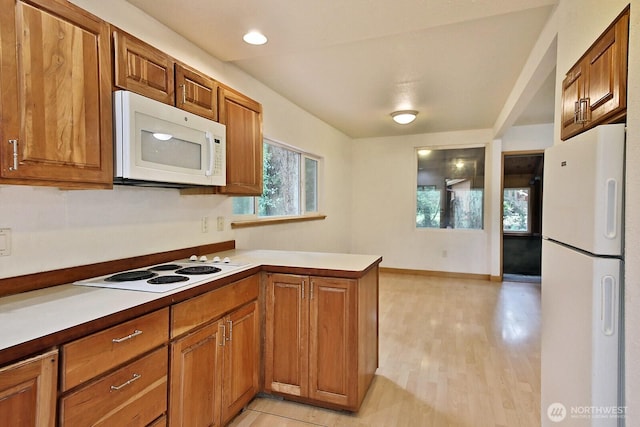 808 Woodsong Ln, Langley, WA 98260 - kitchen featuring white appliances, brown cabinets, a peninsula, light countertops, and light wood-type flooring