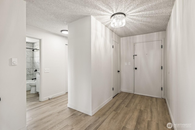 15330 40th Ave W Unit A & B, Lynnwood, WA 98087 - hallway with a textured ceiling, light wood-type flooring, a chandelier, and baseboards