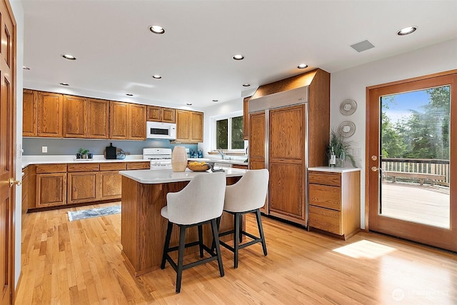 29247 188th Ave SE, Kent, WA 98042 - kitchen with white appliances, brown cabinetry, light wood-type flooring, a center island, and recessed lighting