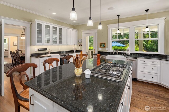 19840 Vashon Hwy SW, Vashon, WA 98070 - kitchen with appliances with stainless steel finishes, white cabinets, a kitchen island, dark wood-style flooring, and ornamental molding
