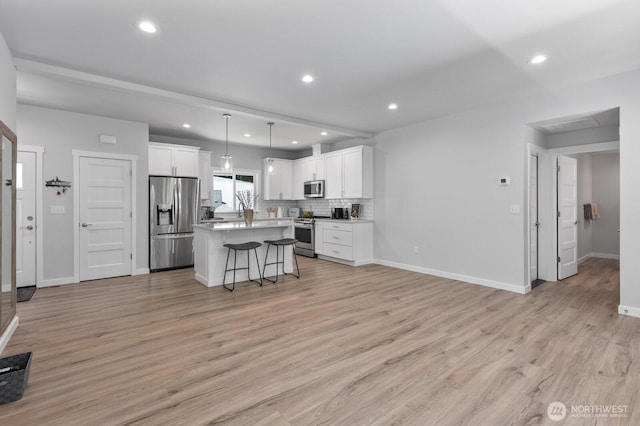 18207 Majestic Ridge Ln, Mount Vernon, WA 98274 - kitchen featuring stainless steel appliances, a breakfast bar area, a center island, white cabinets, and light wood-style floors