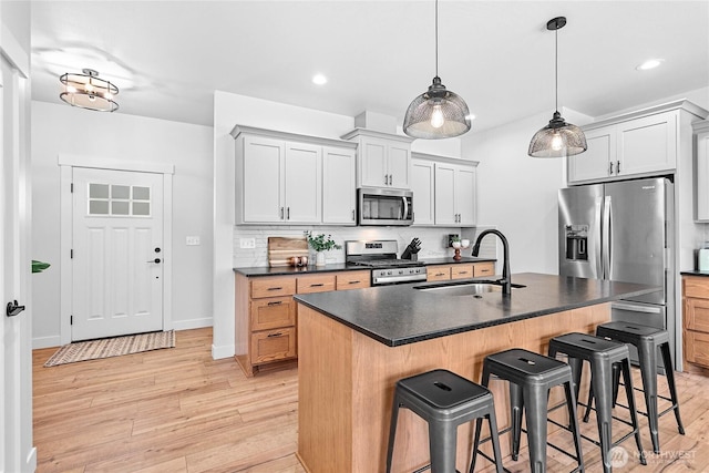 2183 Lagerwey Cir, Lynden, WA 98264 - kitchen with appliances with stainless steel finishes, dark countertops, a kitchen bar, backsplash, and light wood finished floors