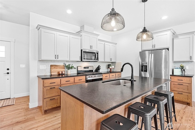 2183 Lagerwey Cir, Lynden, WA 98264 - kitchen featuring stainless steel appliances, dark countertops, a kitchen breakfast bar, decorative backsplash, and light wood-type flooring